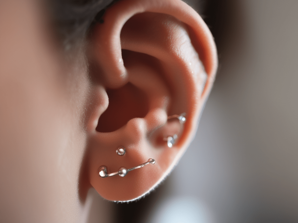 Das Bild zeigt ein menschliches Ohr mit verschiedenen ohrsteckern in Gold und Silber
